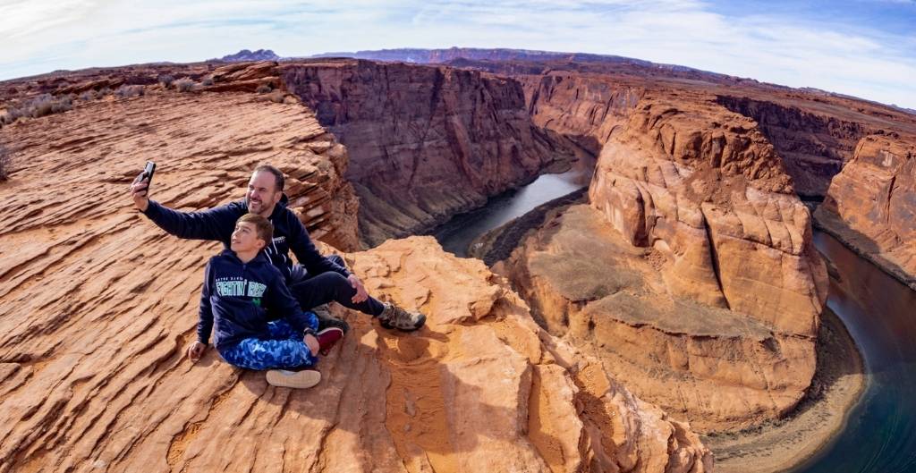 father and son taking a selfie above horseshoe bend
