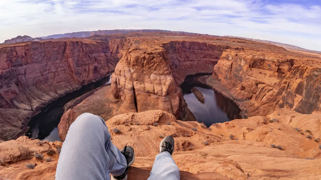 person sitting on the edge of Horseshoe Bend