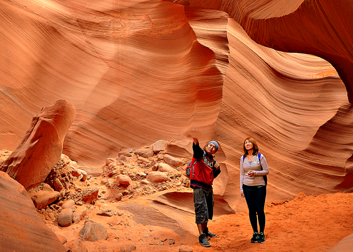 two people looking up at the walls of antelope canyon and pointing