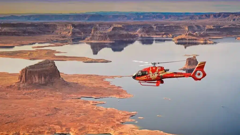 red helicopter flying over grand canyon