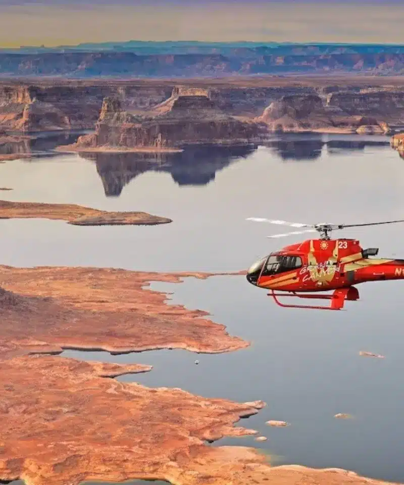 red helicopter flying over grand canyon