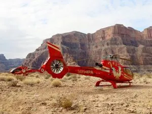 red helicopter landed on the edge of the grand canyon