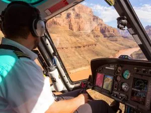 pilot flying a helicopter over the grand canyon