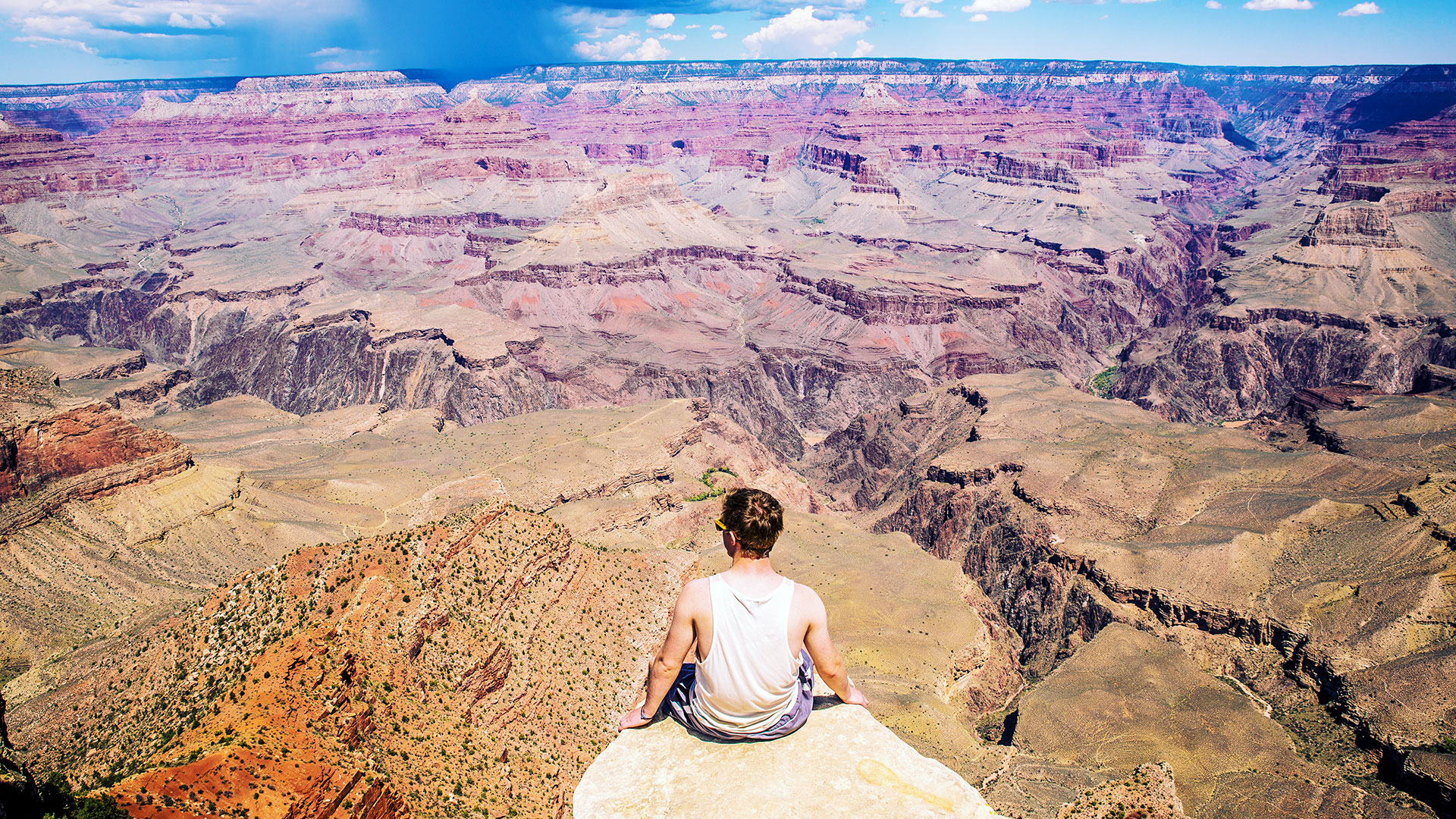 person sitting on a ledge overlooking the grand canyon
