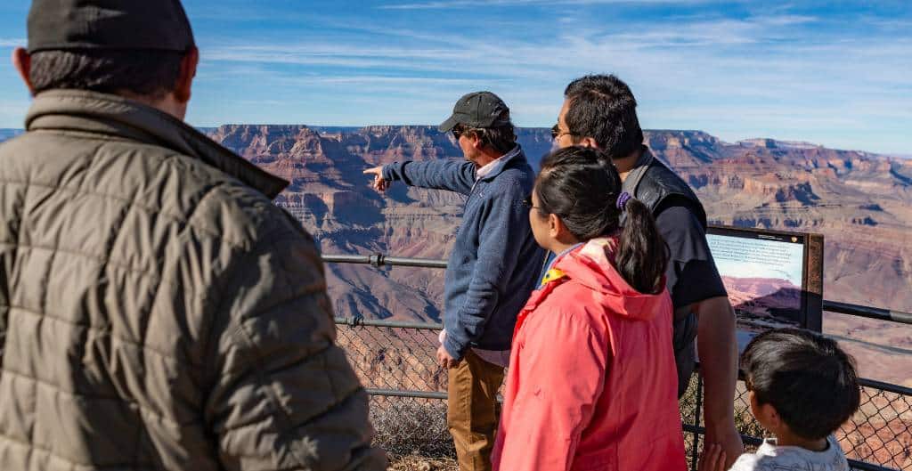 a family listening to a guide during a tour of the grand canyon