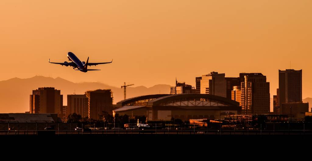 jet taking off from phoenix airport in front of orange sky