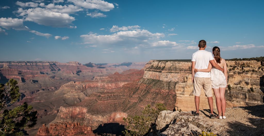 couple with arms around each other looking out over the grand canyon