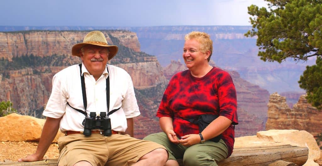 a couple sitting on the a bench with the grand canyon in the background