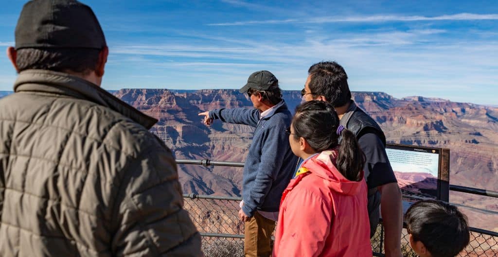 family listening to guide point out something from a grand canyon overlook