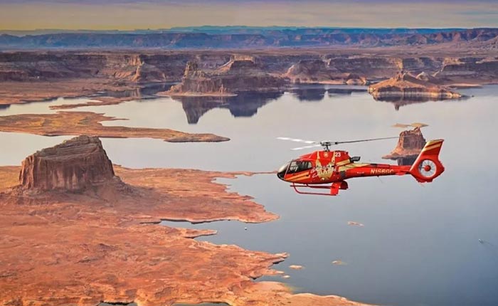 red helicopter flying over grand canyon