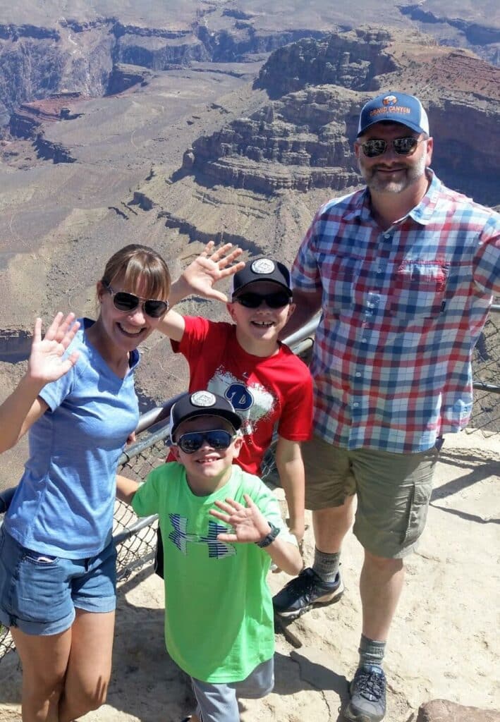 A family poses in front of a Grand Canyon overlook with a local tour guide