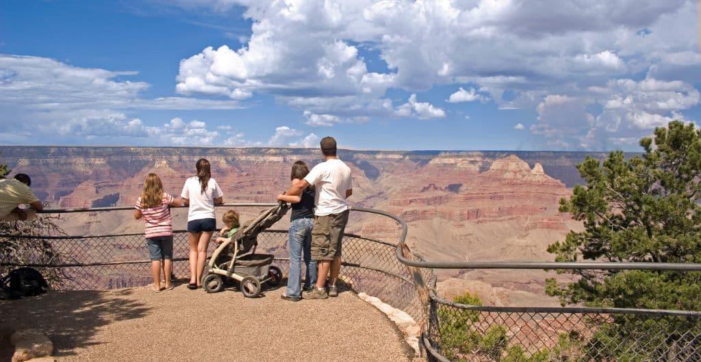 A family with a stroller looks out at the grand canyon