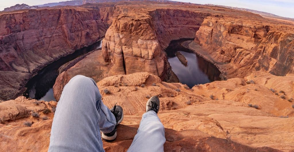 A person sits and looks out at horseshoe bend